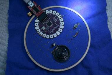 lilypad arduino and small circuit in an embroydery hoop, light shinin on one part