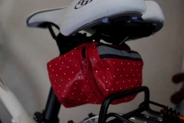 red bag with white polka dots hangs under the bike seat